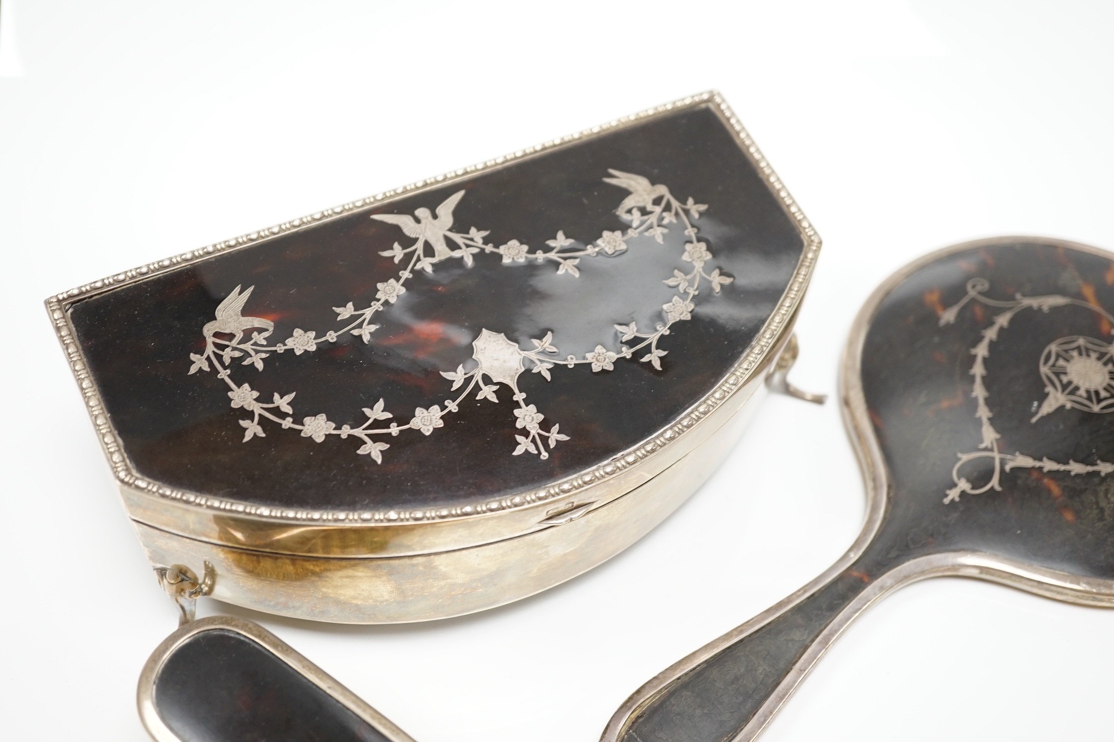 A George V silver and tortoiseshell piqué mounted trinket box, Levi & Salaman, Birmingham, 1918, 19cm and a matched three piece silver and tortoiseshell mounted mirror and brush set.